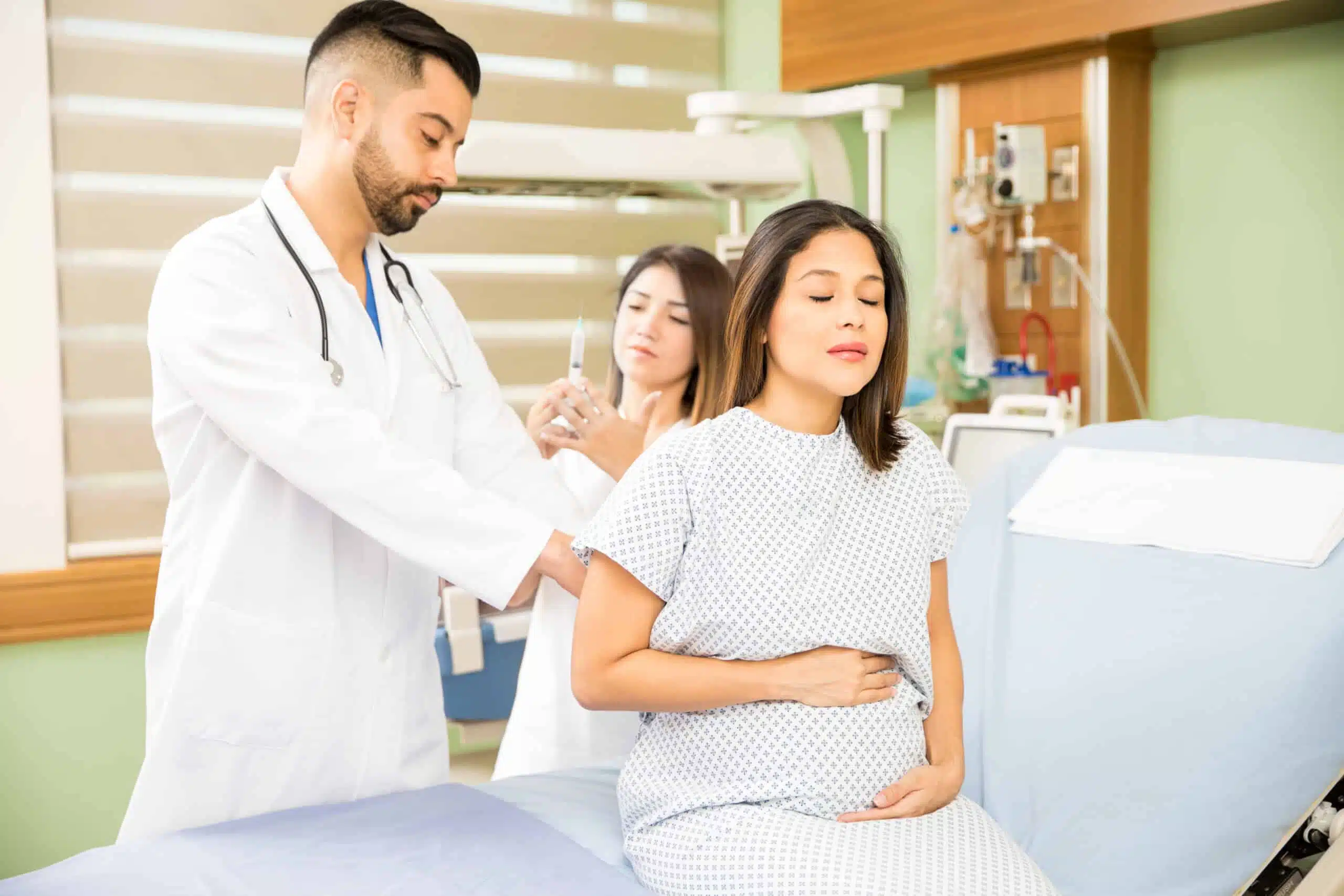 Couple of doctors about to give a shot to a pregnant woman in a hospital