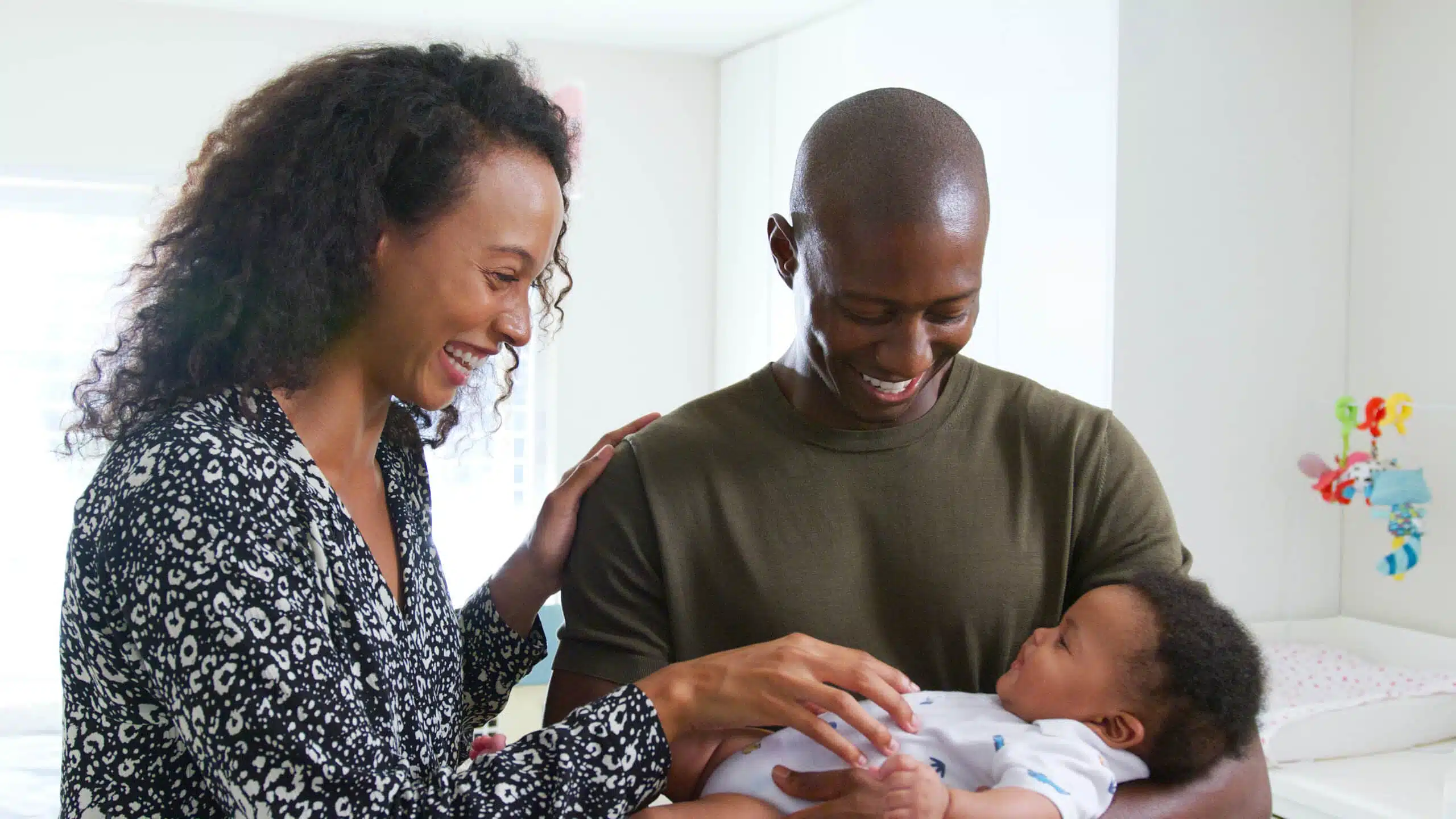 Loving Parents Standing In Nursery At Home Cuddling Baby Son