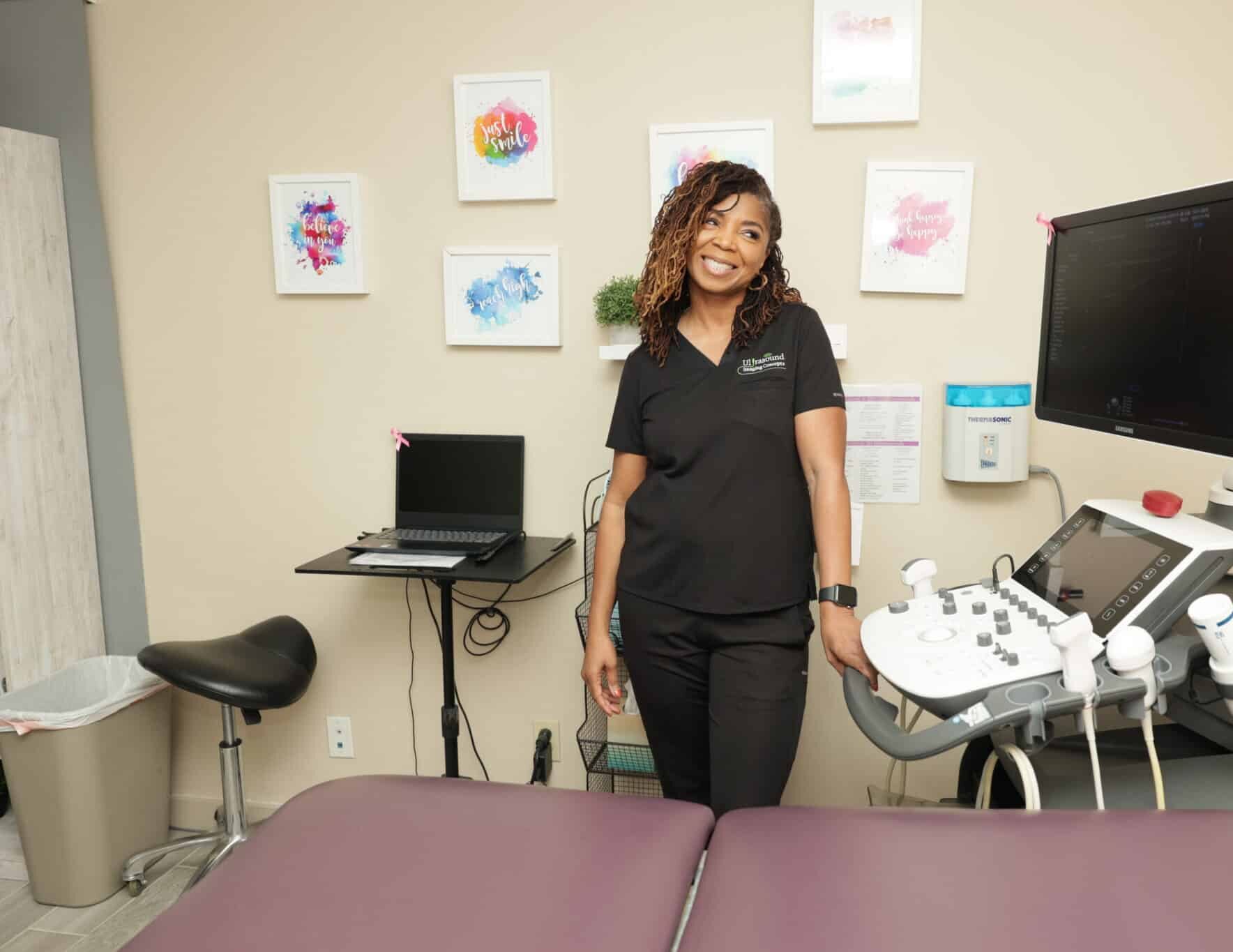 Smiling ultrasound business owner standing beside ultrasound machine in exam room